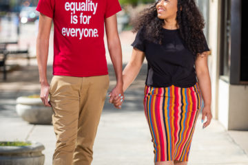 Photo of a couple walking down a city street and holding hands.