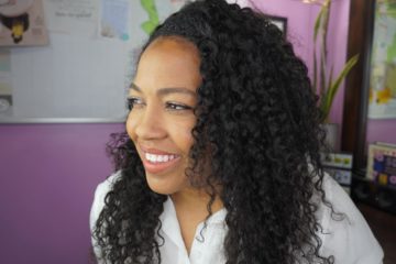 woman with curly hair smiling and looking away from the camera